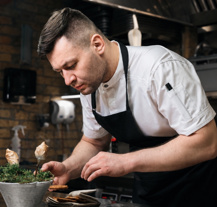Kucharz komponujący danie w restauracyjnej kuchni