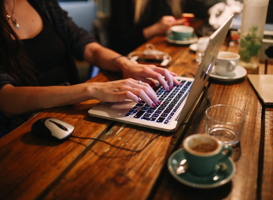 Osoba pracująca na laptopie przy filiżance kawy